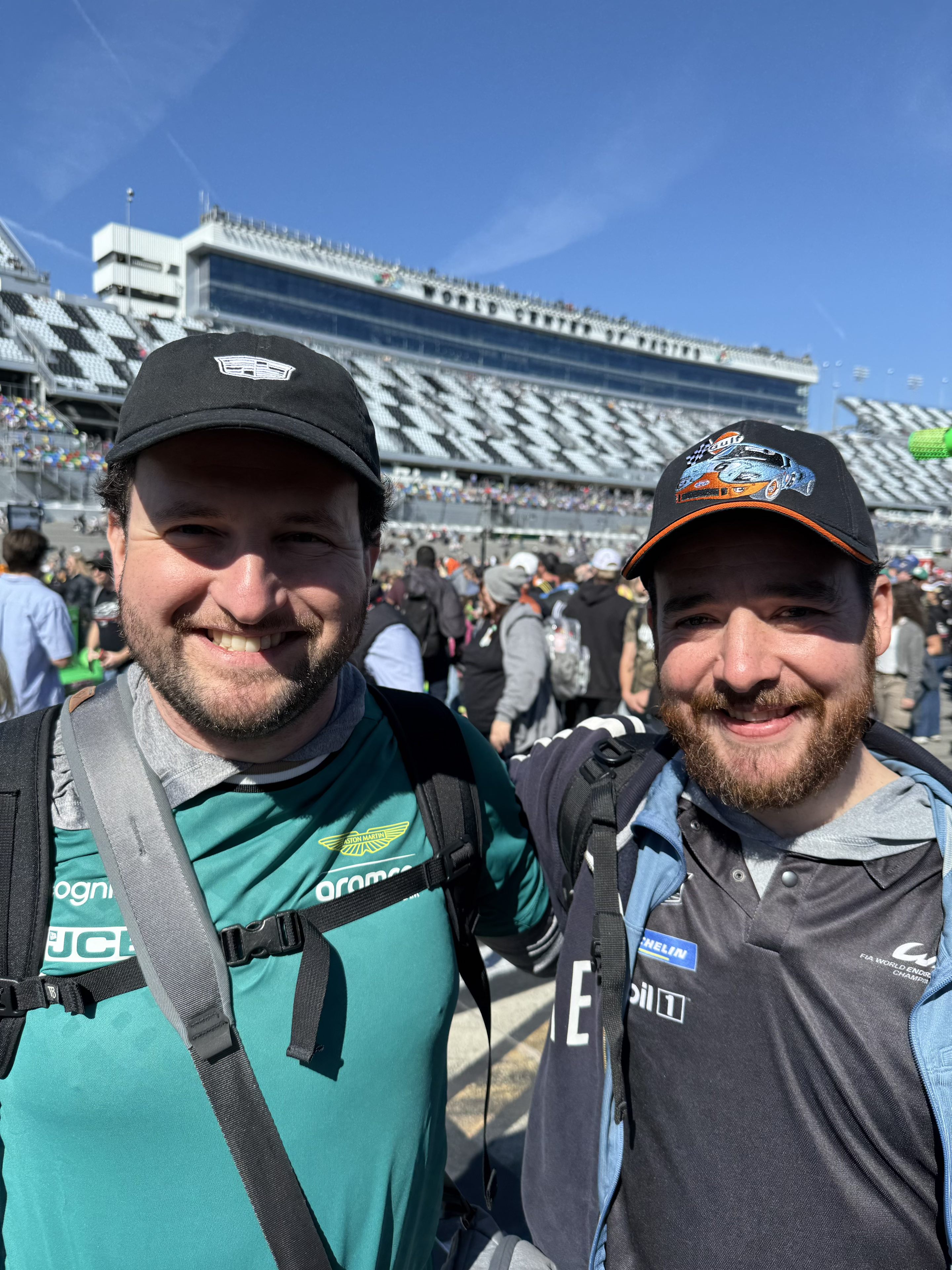 Two thirtysomethingish men in racing clothes smiling for a selfie at Daytona International Speedway